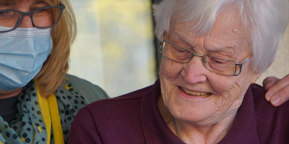 Elderly woman working along side a care giver