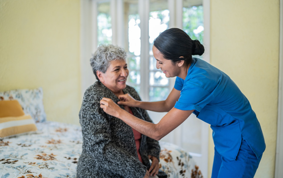 Caregiver helping elderly put on a coat