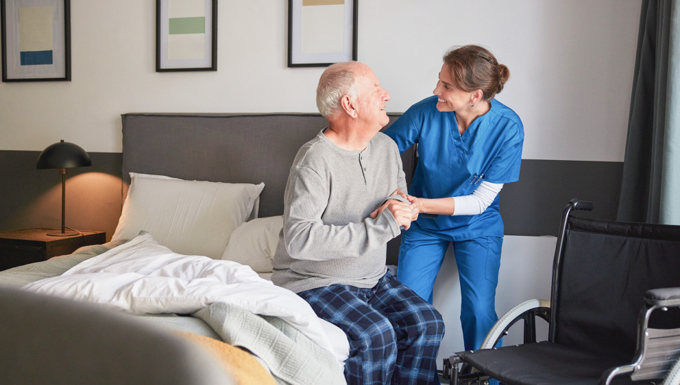 Care giver helping elderly patient out of bed